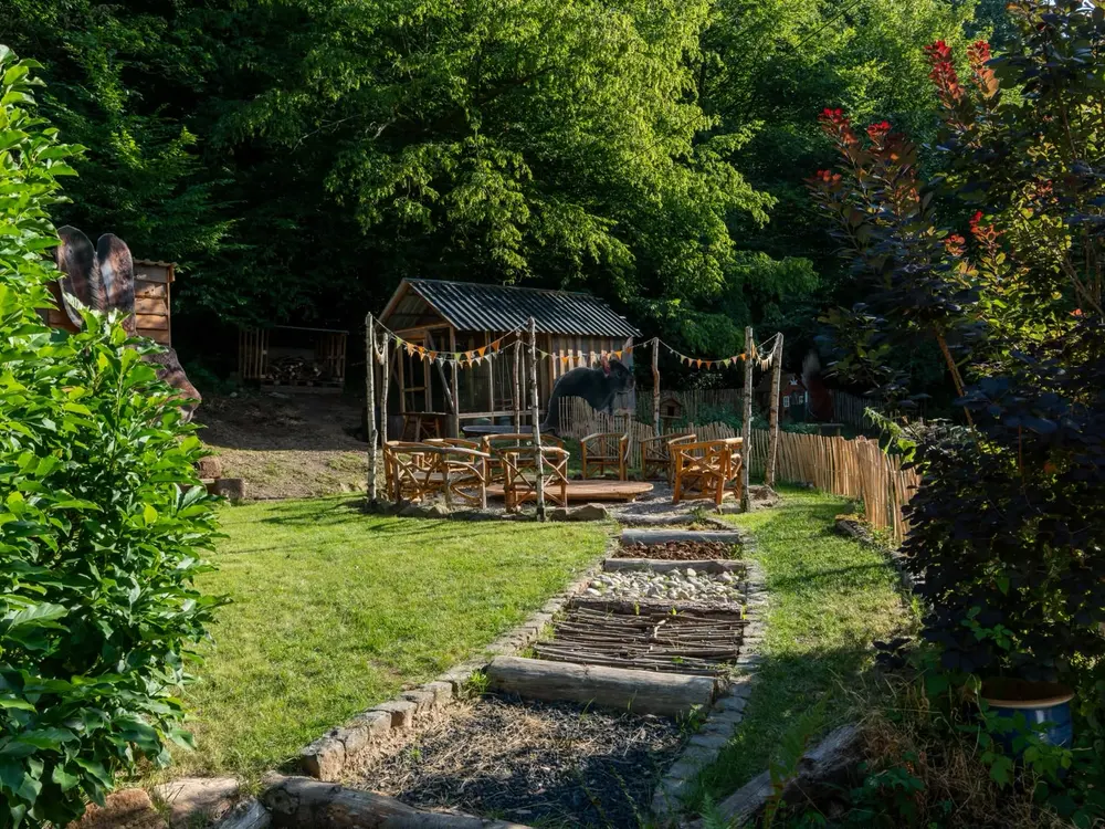 Sitzkreis mit Voliere und Gartenweg auf dem Hofgelände